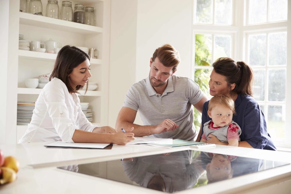 A financial advisors helping a young couple with a baby plan their financial future.